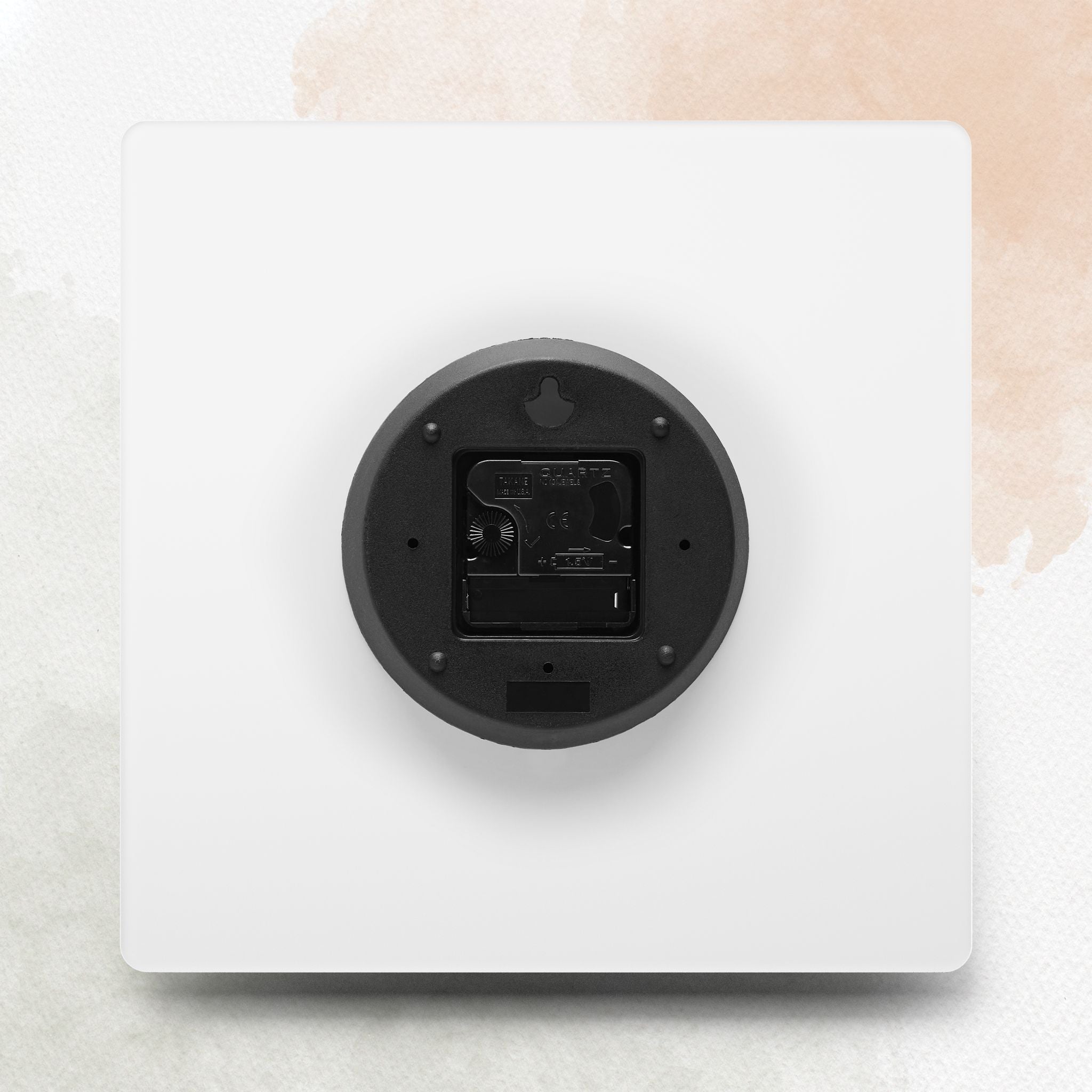 White electronic device with a black circular component on a light beige background