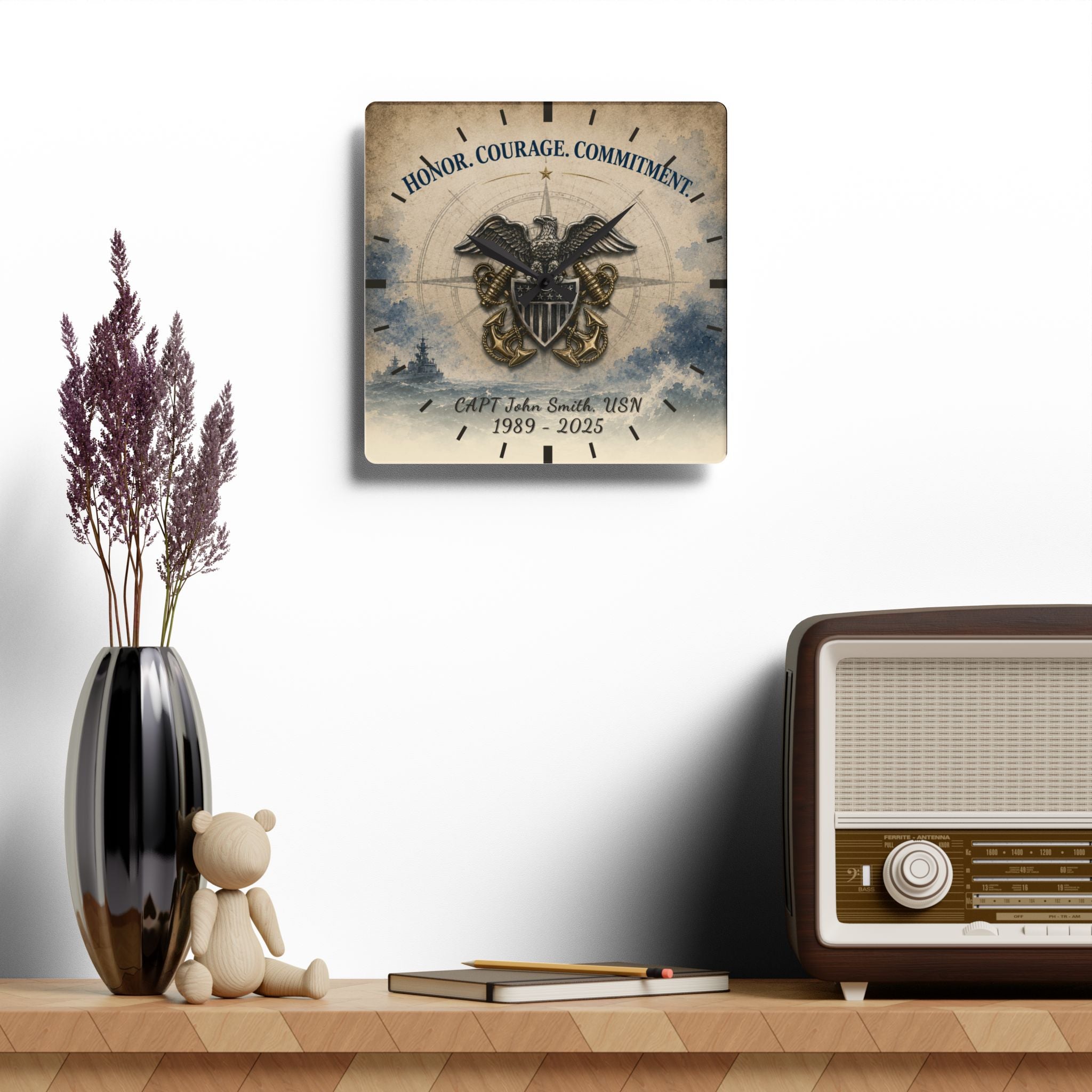 Decorative wall clock with military emblem and text on a shelf with a vase, teddy bear, and radio.