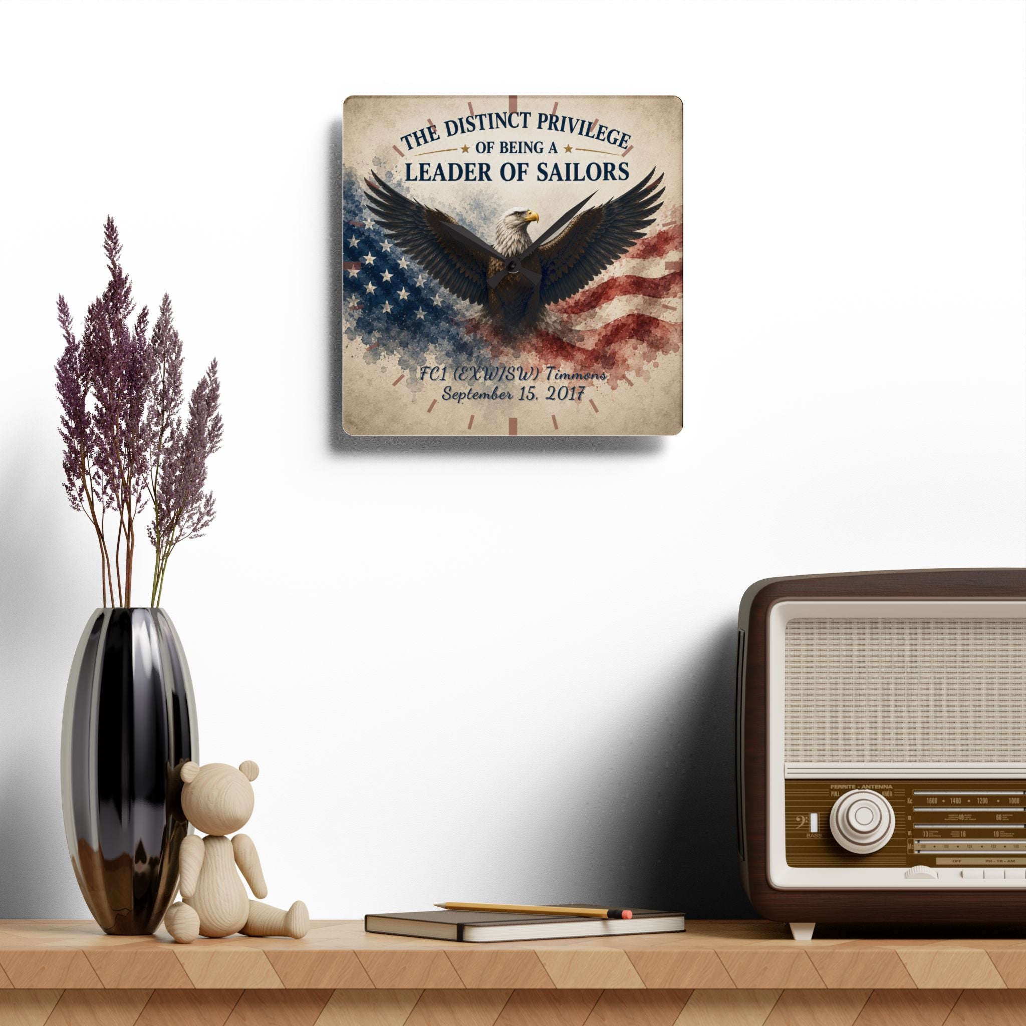 Decorative wall plaque with eagle and American flag design on a shelf with a vase, teddy bear, and radio.
